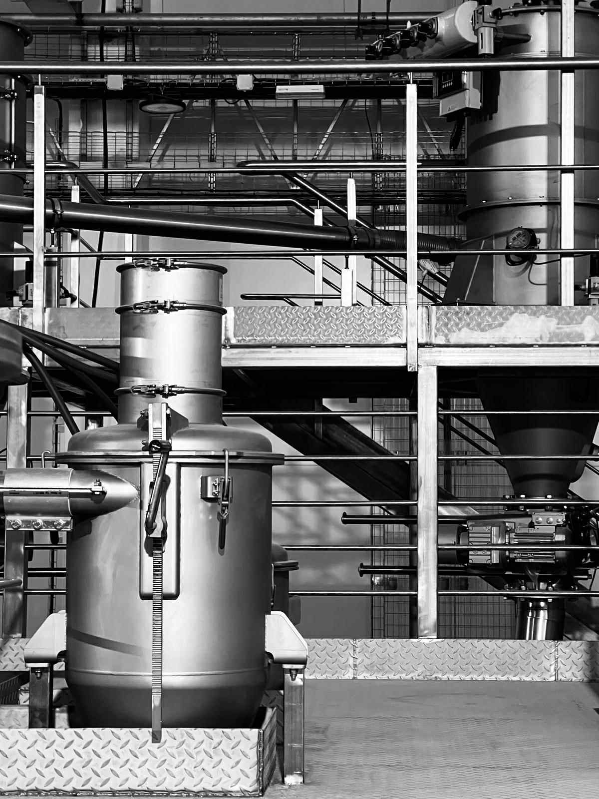 Stainless steel process vessel on a platform with stairs and piping